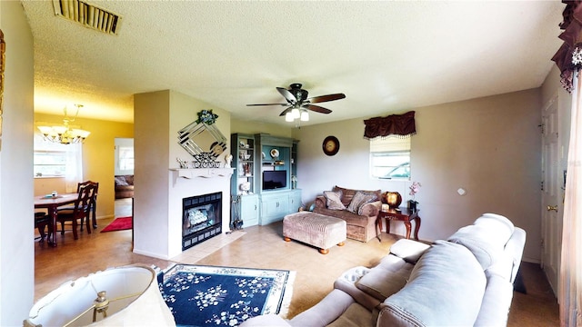 living room featuring a textured ceiling and ceiling fan with notable chandelier