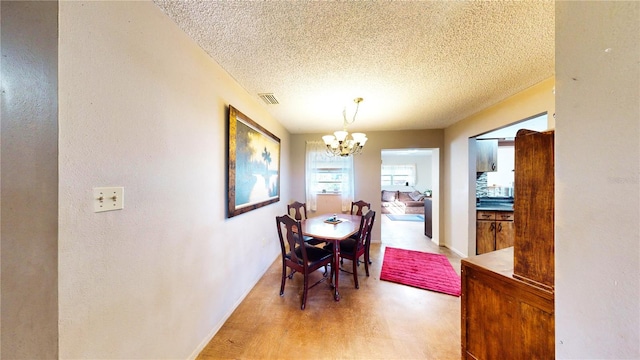 dining space with light wood-type flooring, a textured ceiling, and an inviting chandelier