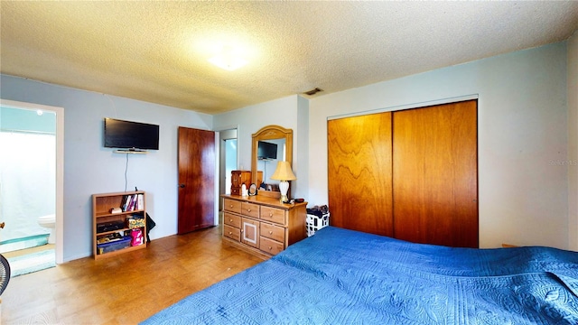 bedroom featuring a closet, wood-type flooring, a textured ceiling, and ensuite bath