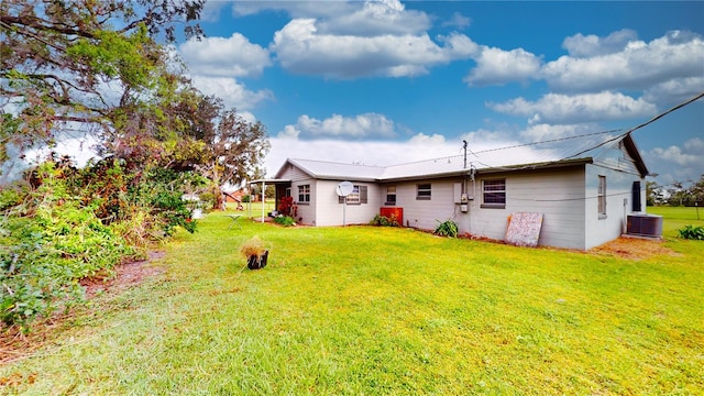 back of property featuring central air condition unit and a yard