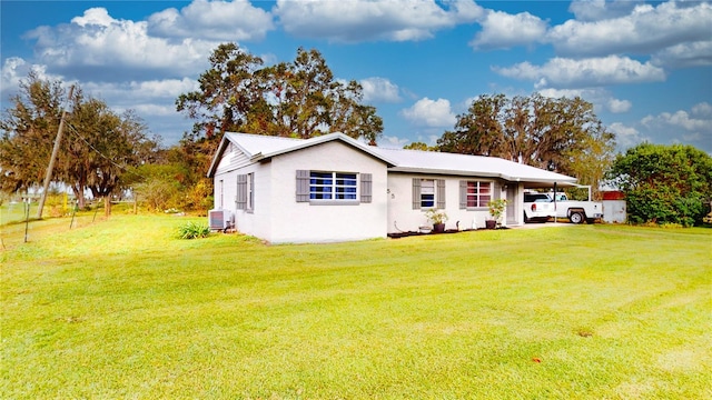 back of property featuring cooling unit and a lawn