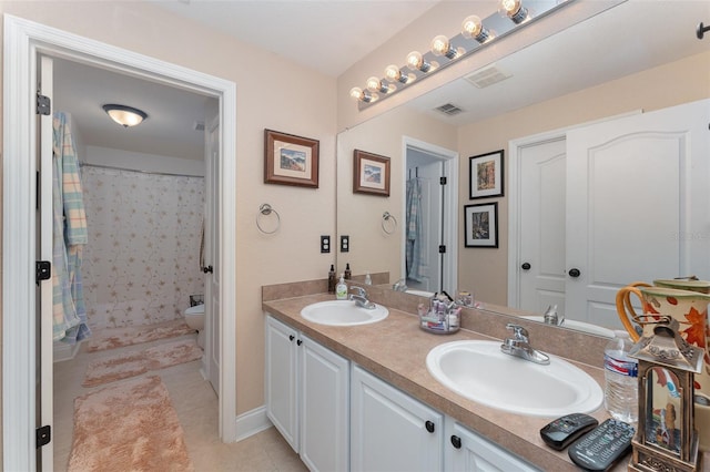 bathroom with toilet, vanity, and tile patterned flooring