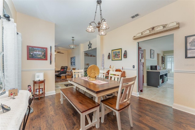 dining space featuring ceiling fan with notable chandelier and hardwood / wood-style flooring