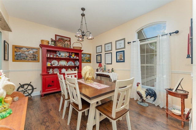 dining room with dark wood-type flooring and a notable chandelier