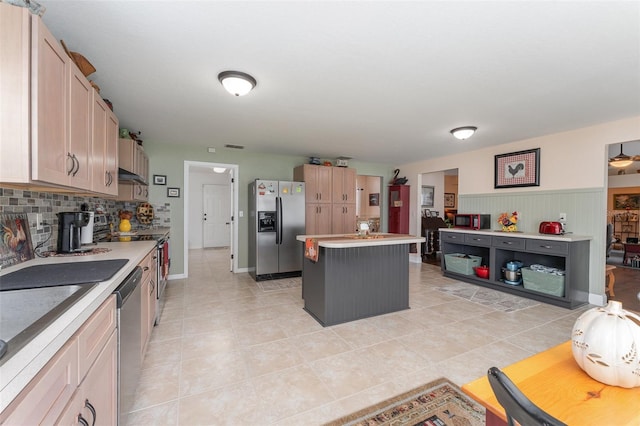 kitchen with light tile patterned floors, appliances with stainless steel finishes, light brown cabinetry, and a kitchen island