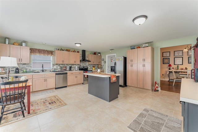 kitchen with appliances with stainless steel finishes, decorative backsplash, light brown cabinets, wall chimney range hood, and a center island