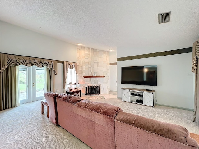 carpeted living room with french doors, a fireplace, and a textured ceiling