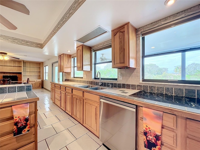 kitchen with tasteful backsplash, sink, tile counters, dishwasher, and ceiling fan