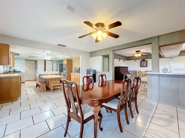 dining room with a textured ceiling, sink, ceiling fan, and light tile patterned floors