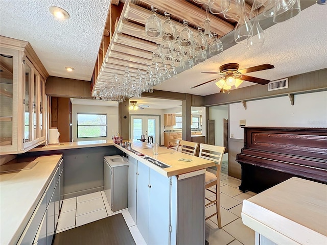 kitchen with wood counters, a textured ceiling, and light tile patterned floors