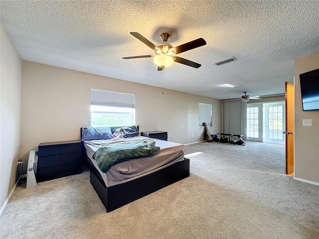 bedroom with multiple windows, a textured ceiling, light colored carpet, and ceiling fan