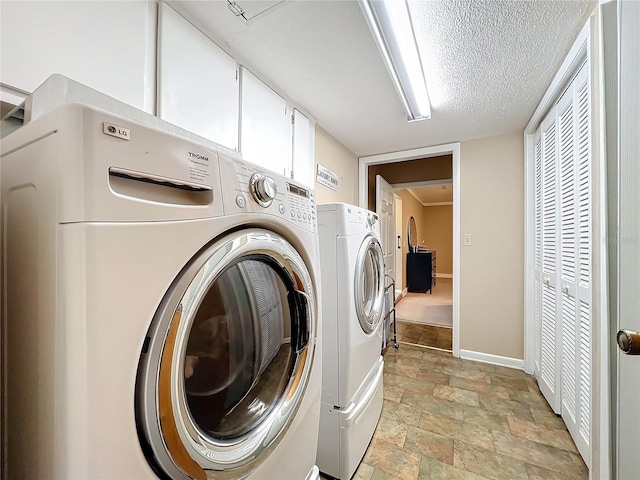 laundry area with washer and clothes dryer, cabinets, and a textured ceiling