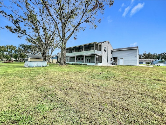 rear view of house featuring central AC unit, a sunroom, and a yard