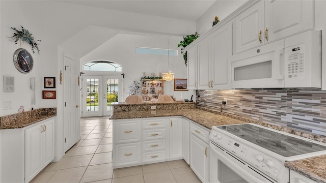 kitchen with kitchen peninsula, white appliances, light tile patterned floors, and white cabinets