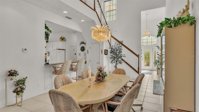 dining room with a chandelier, light tile patterned flooring, and a towering ceiling