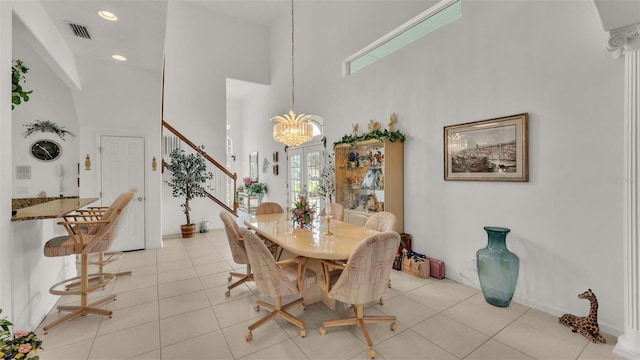 dining area featuring a towering ceiling, light tile patterned flooring, and a notable chandelier