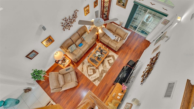 living room featuring hardwood / wood-style flooring, a towering ceiling, and ceiling fan