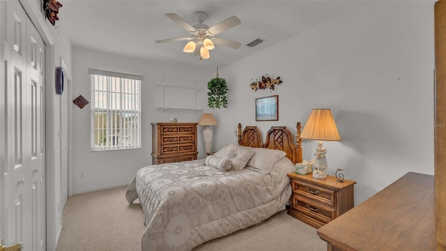 bedroom with light colored carpet, ceiling fan, and a closet