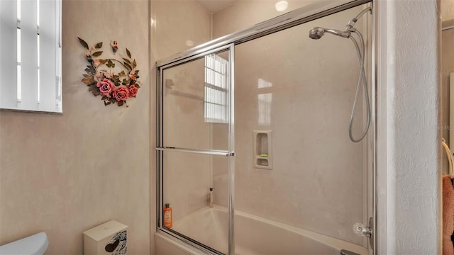 bathroom featuring enclosed tub / shower combo and toilet