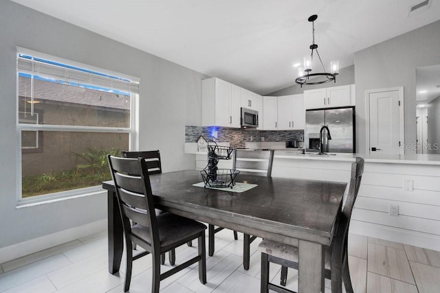 dining area with a healthy amount of sunlight, an inviting chandelier, and vaulted ceiling