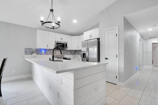 kitchen featuring stainless steel appliances, white cabinetry, decorative light fixtures, vaulted ceiling, and kitchen peninsula