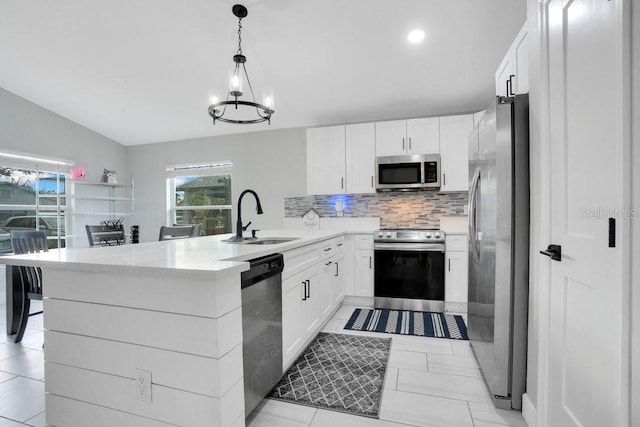 kitchen with stainless steel appliances, kitchen peninsula, hanging light fixtures, sink, and white cabinetry