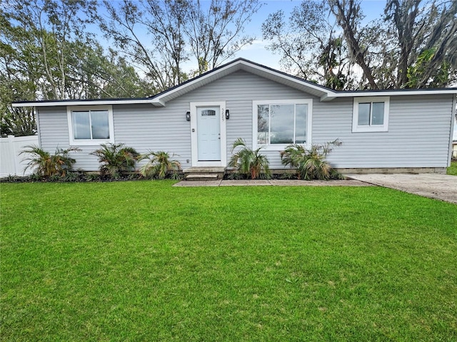 ranch-style house featuring fence and a front lawn