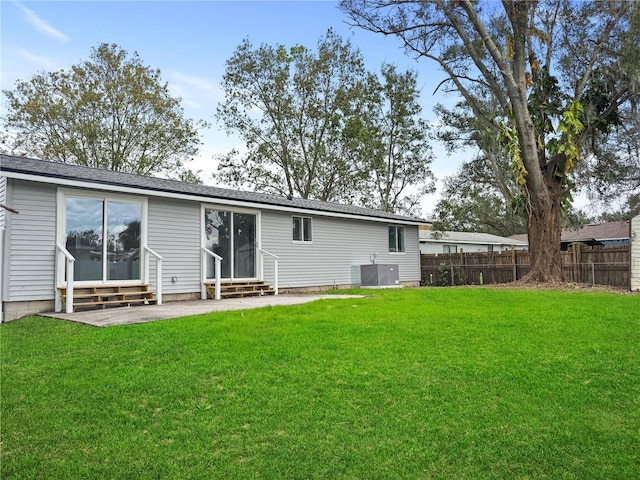 back of property with entry steps, a lawn, cooling unit, and fence