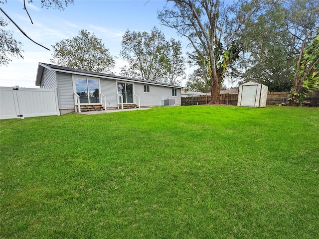 back of property with a lawn, central AC unit, and a shed