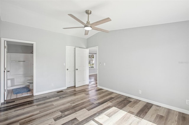 unfurnished bedroom with ceiling fan, light hardwood / wood-style flooring, connected bathroom, and vaulted ceiling