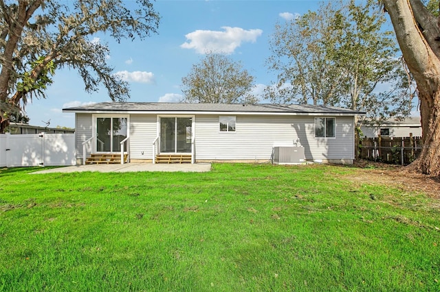 rear view of property with a yard and central AC