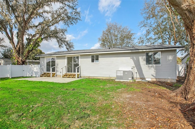 rear view of house with a yard and cooling unit