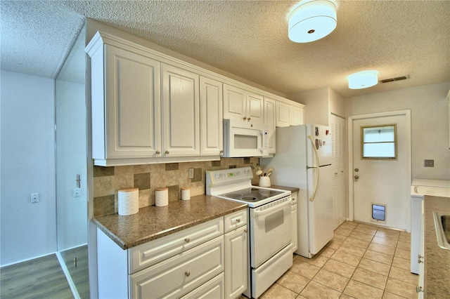 kitchen featuring white cabinetry, a textured ceiling, white appliances, and light tile patterned floors