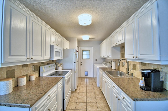 kitchen featuring washer and clothes dryer, white cabinetry, white appliances, and sink