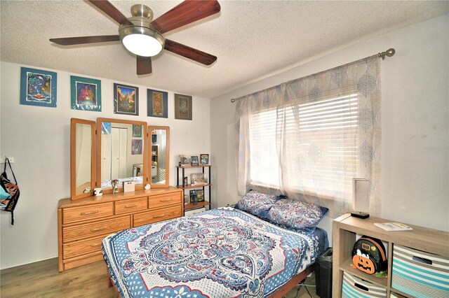 bedroom featuring ceiling fan, a textured ceiling, and wood-type flooring