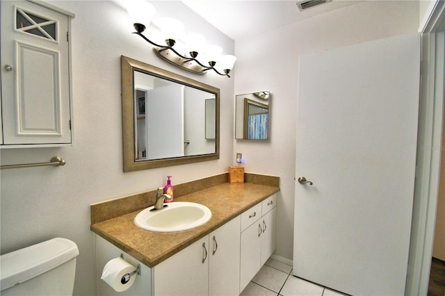 bathroom with toilet, vanity, and tile patterned flooring