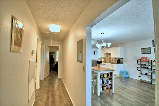 corridor featuring electric panel, a textured ceiling, and light hardwood / wood-style flooring