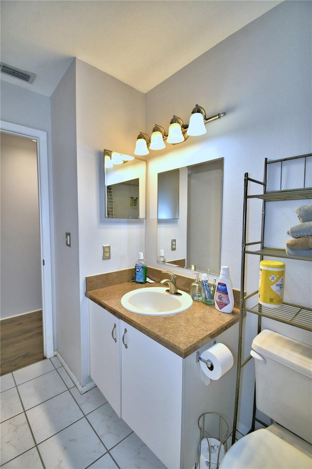 bathroom with toilet, vanity, and wood-type flooring