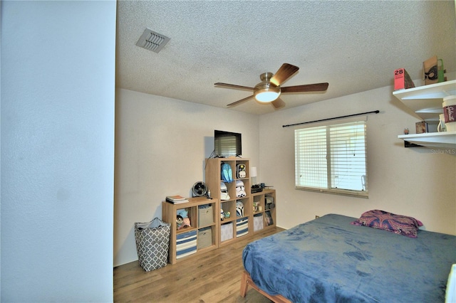 bedroom with wood-type flooring, ceiling fan, and a textured ceiling