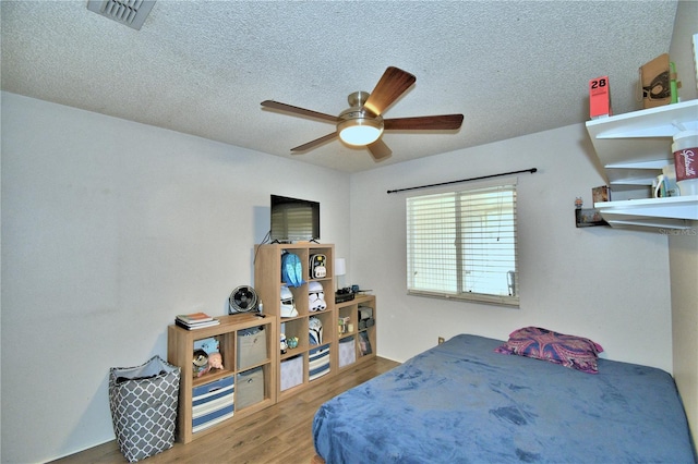 bedroom featuring hardwood / wood-style floors, ceiling fan, and a textured ceiling