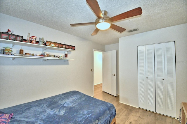 bedroom featuring a textured ceiling, light hardwood / wood-style floors, ceiling fan, and a closet