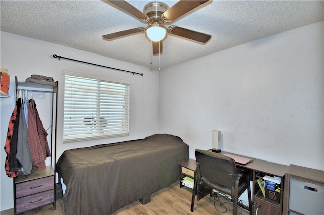 bedroom with light hardwood / wood-style floors, ceiling fan, and a textured ceiling