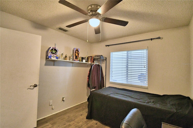 bedroom with a textured ceiling, hardwood / wood-style flooring, and ceiling fan