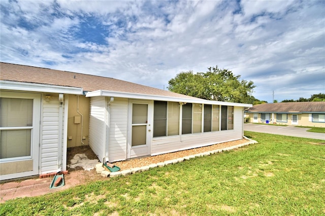 view of side of property with a sunroom and a yard