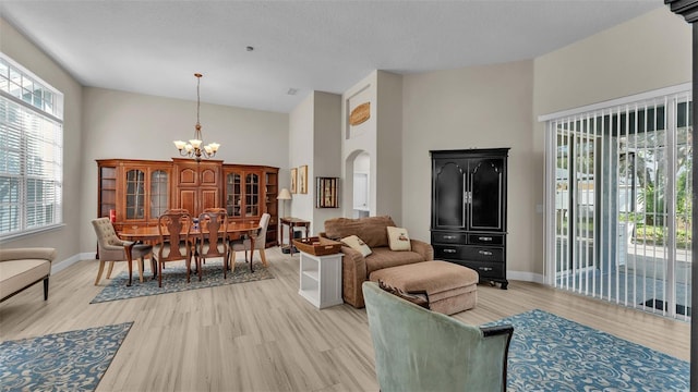 living room with a high ceiling, light wood-type flooring, and an inviting chandelier