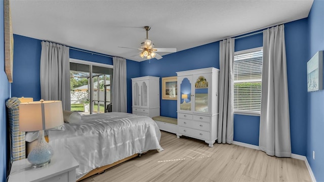 bedroom featuring access to exterior, light hardwood / wood-style floors, multiple windows, and ceiling fan