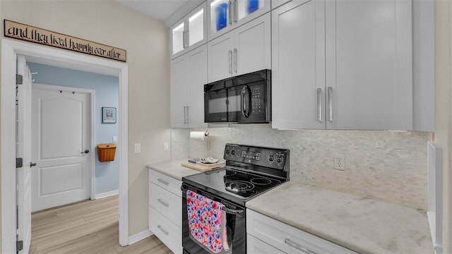 kitchen with white cabinetry, light stone countertops, light hardwood / wood-style flooring, backsplash, and black appliances