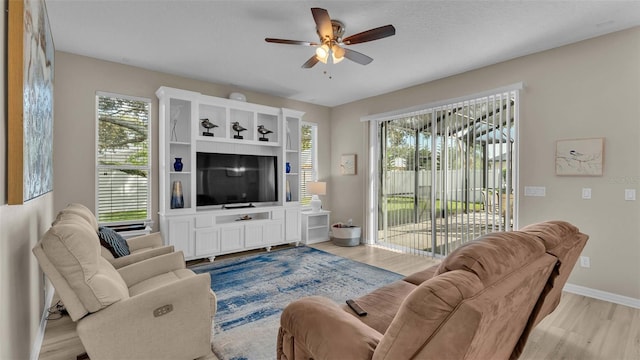 living room with ceiling fan, light wood-type flooring, and a wealth of natural light