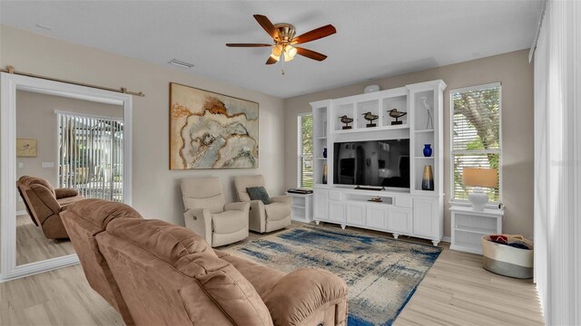 living room with light hardwood / wood-style flooring, plenty of natural light, and ceiling fan