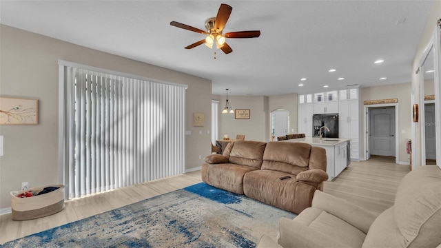 living room with light hardwood / wood-style flooring, ceiling fan, and sink